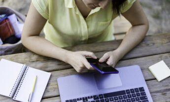 University student checking his cell phone and computer