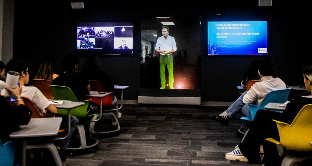 A professor gives a lecture through hologram technology to a class of students