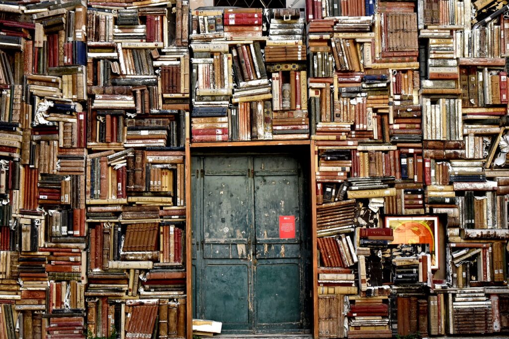 a pile of books in a messy bookshelf and a door
