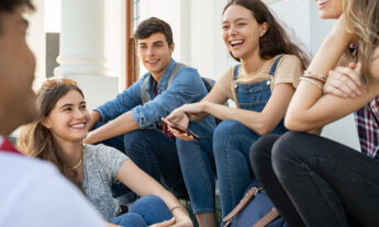A group of teens gather together laughing