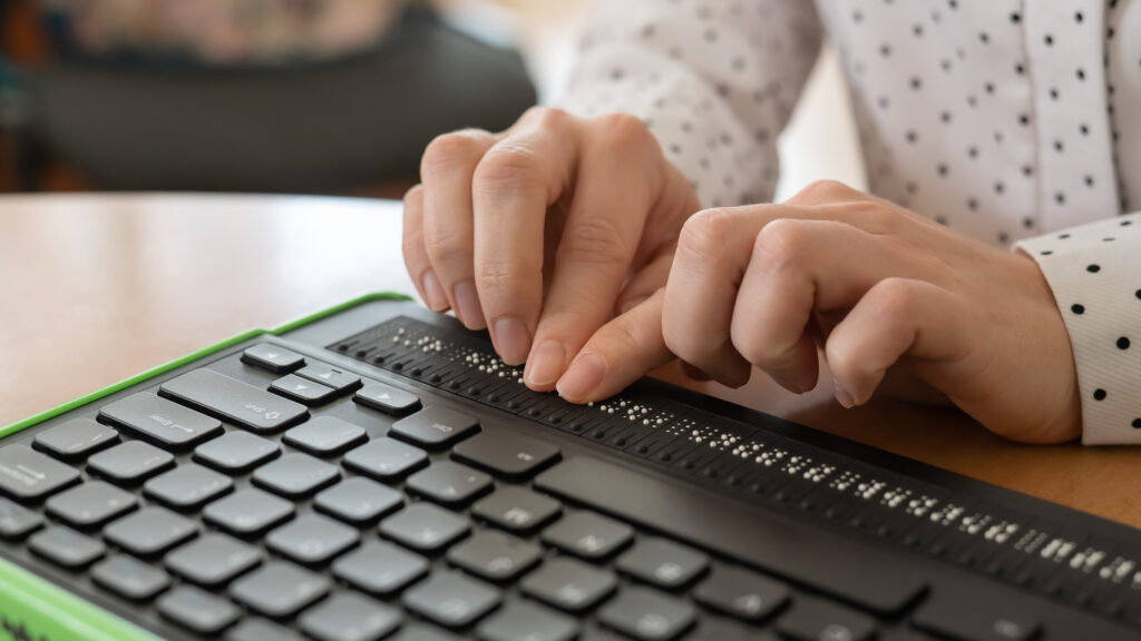 A blind person uses a computer with a Braille keyboard.