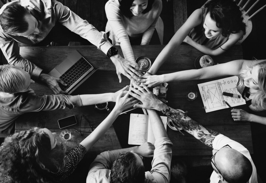 People in a circle join hands to work together.