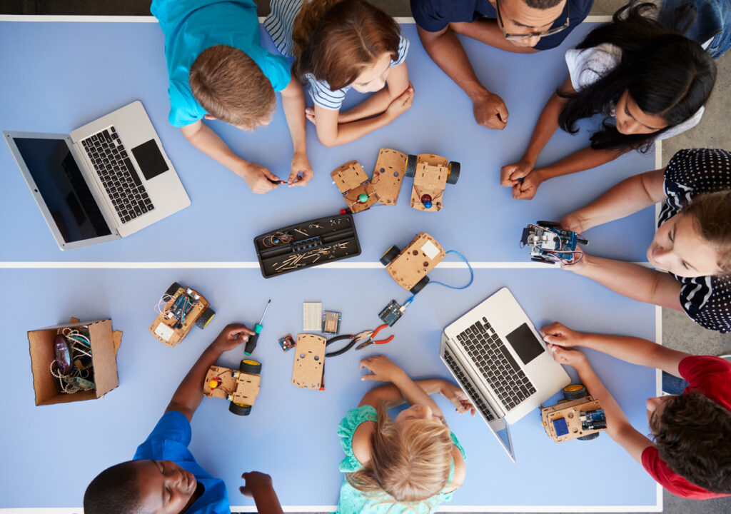 A photo of a group of students working on a project using technology devices and hands on activities