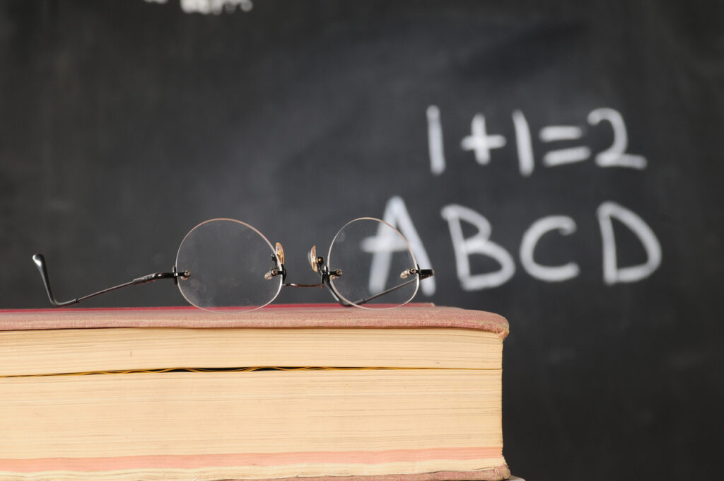 glasses over a book and a blackboard