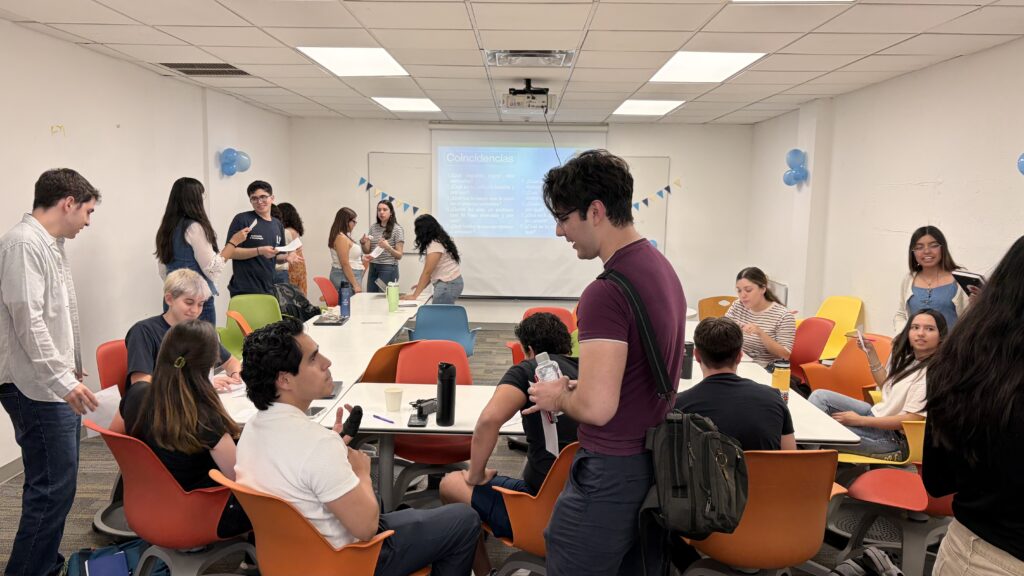 University students participate in a collaborative classroom activity, working in groups and discussing ideas around tables.