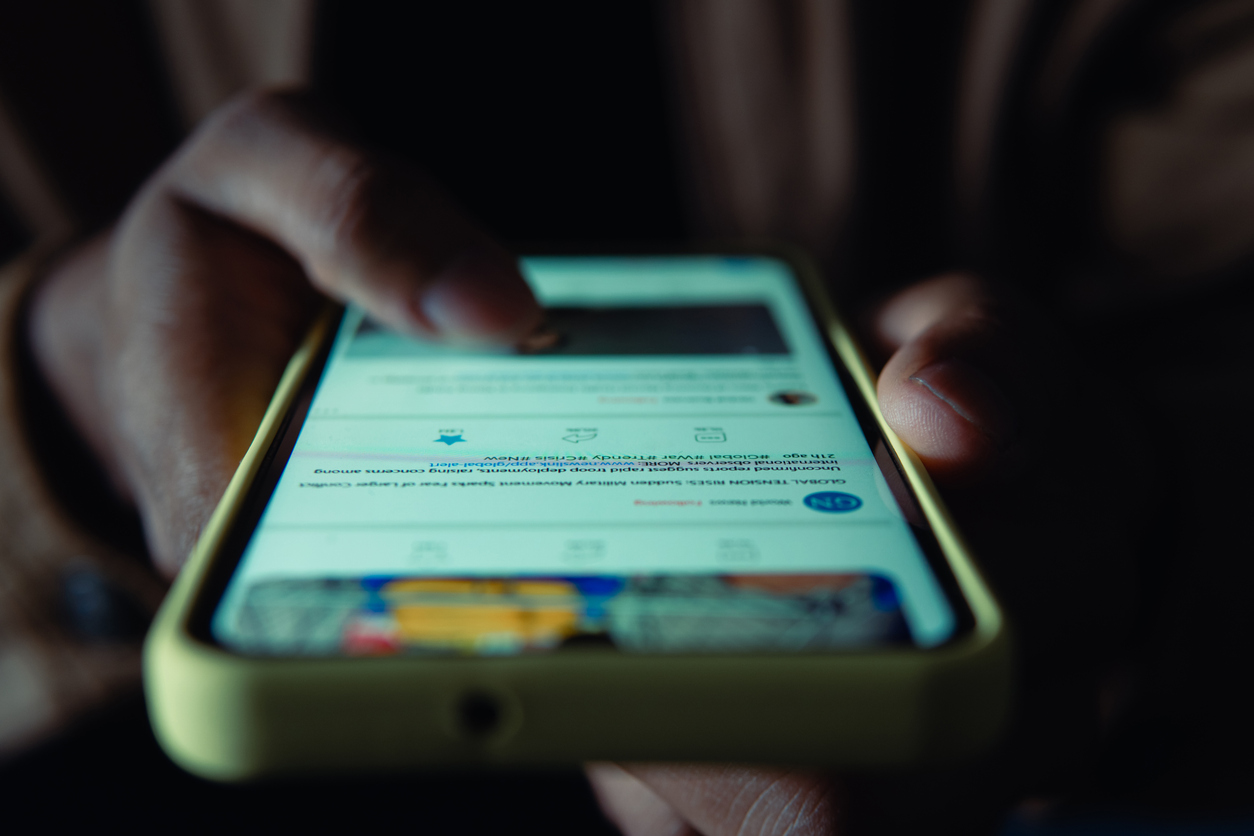 Person scrolling news feed on a phone.
